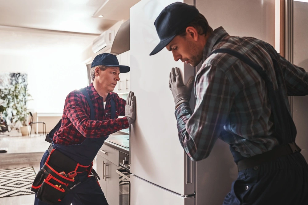 Professional appliance technician repairing refrigerator in Los Angeles home with tools and diagnostic equipment