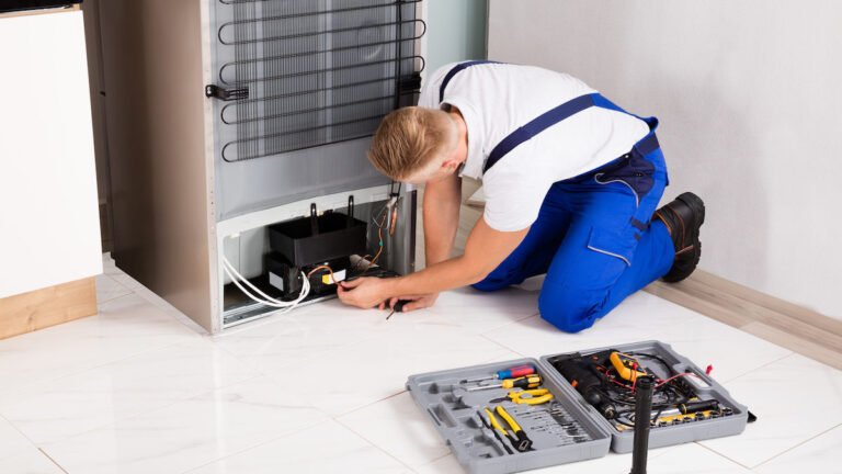Samsung appliance technician repairing refrigerator in Los Angeles home with diagnostic tools and replacement parts